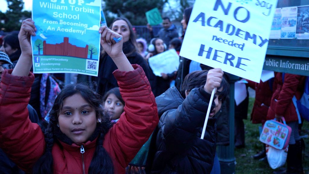 Girl holds poster for no to academies campaign